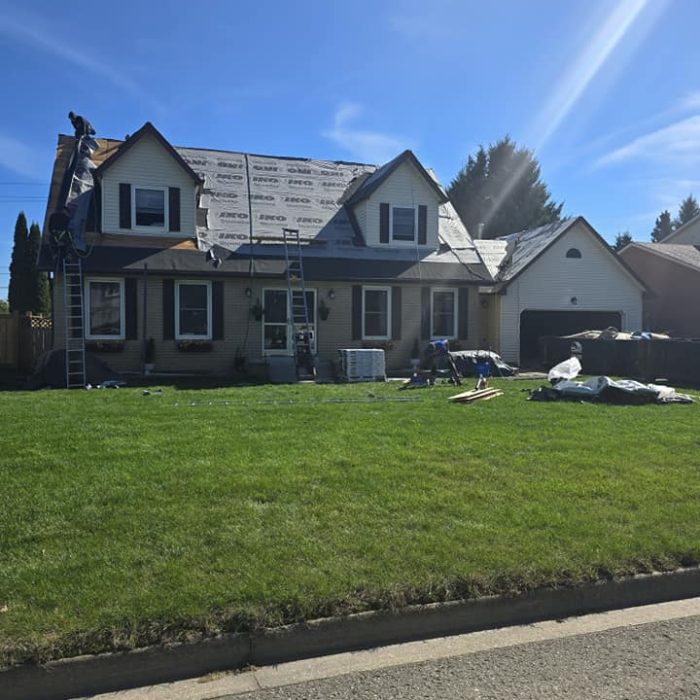 Home in process of roof repair on a sunny day. Ladders and materials visible. Reliable Roofing Solutions.