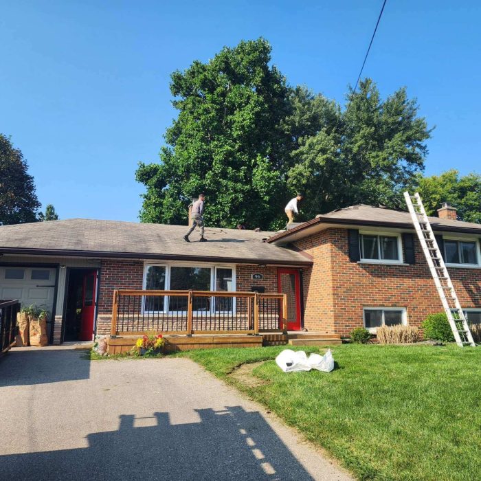 Roofers repairing a residential roof on a sunny day.