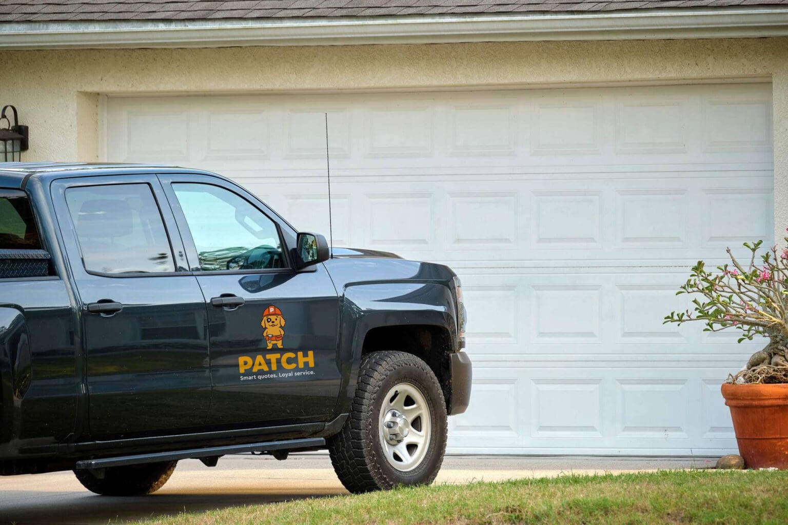 Patch company truck parked in front of a white garage, showcasing home repair services.
